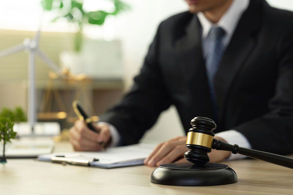 tax lawyer working on paperwork in his office. he is wearing a black suit and navy blue tye