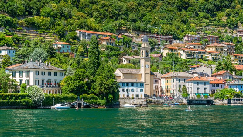 french coast line with buildings along the water surrounded by green trees