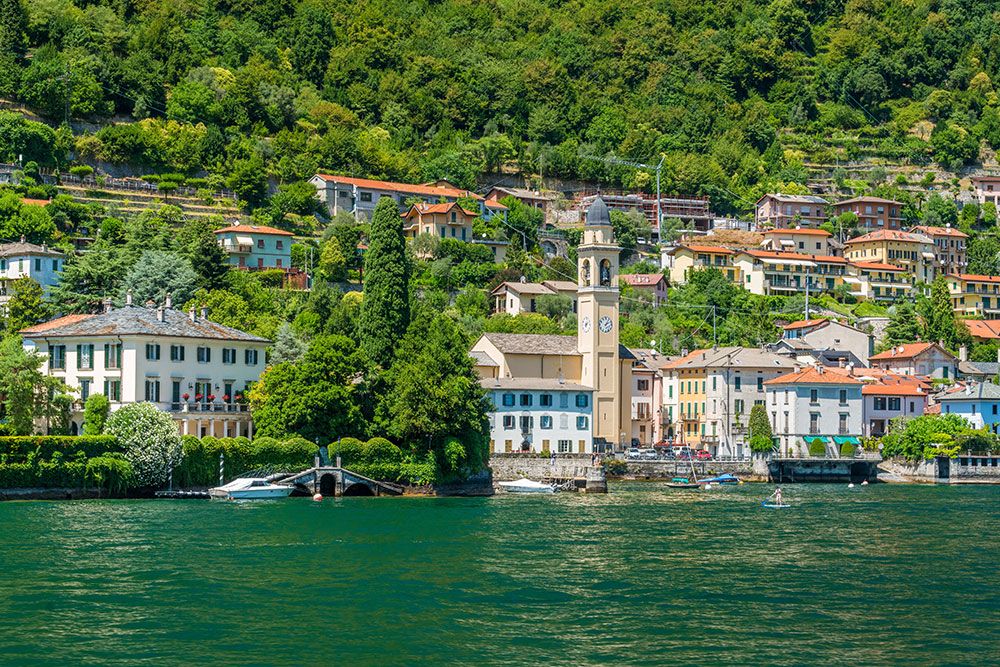 french coast line with buildings along the water surrounded by green trees